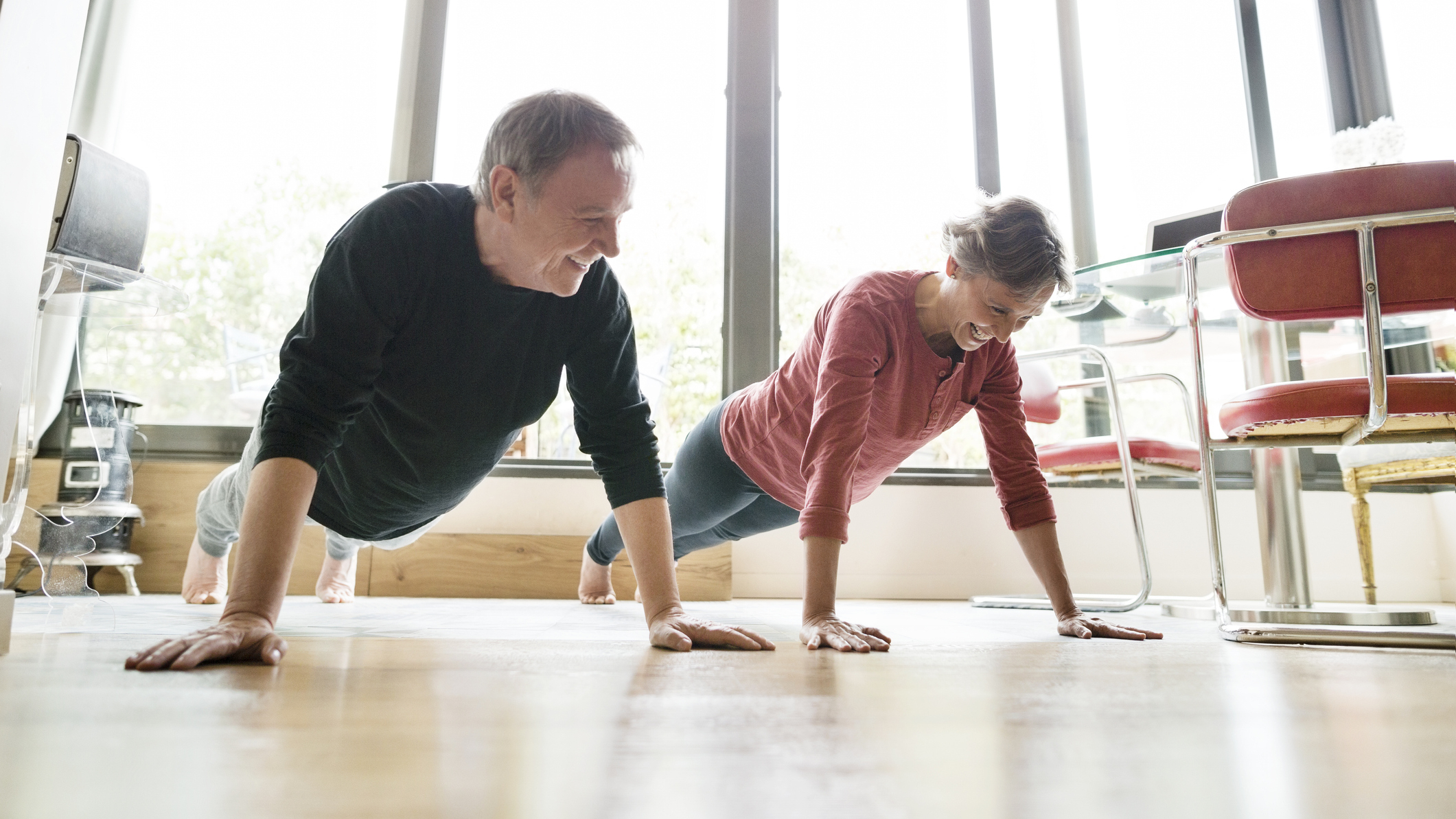 Man and woman in push-up position in domestic setting