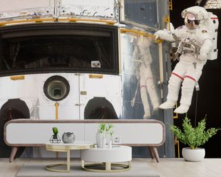 Space wall mural featuring astronaut, with low console and round nesting tables in white and gold.