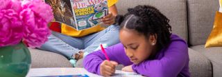 A girl writing something in a magazine with a pencil