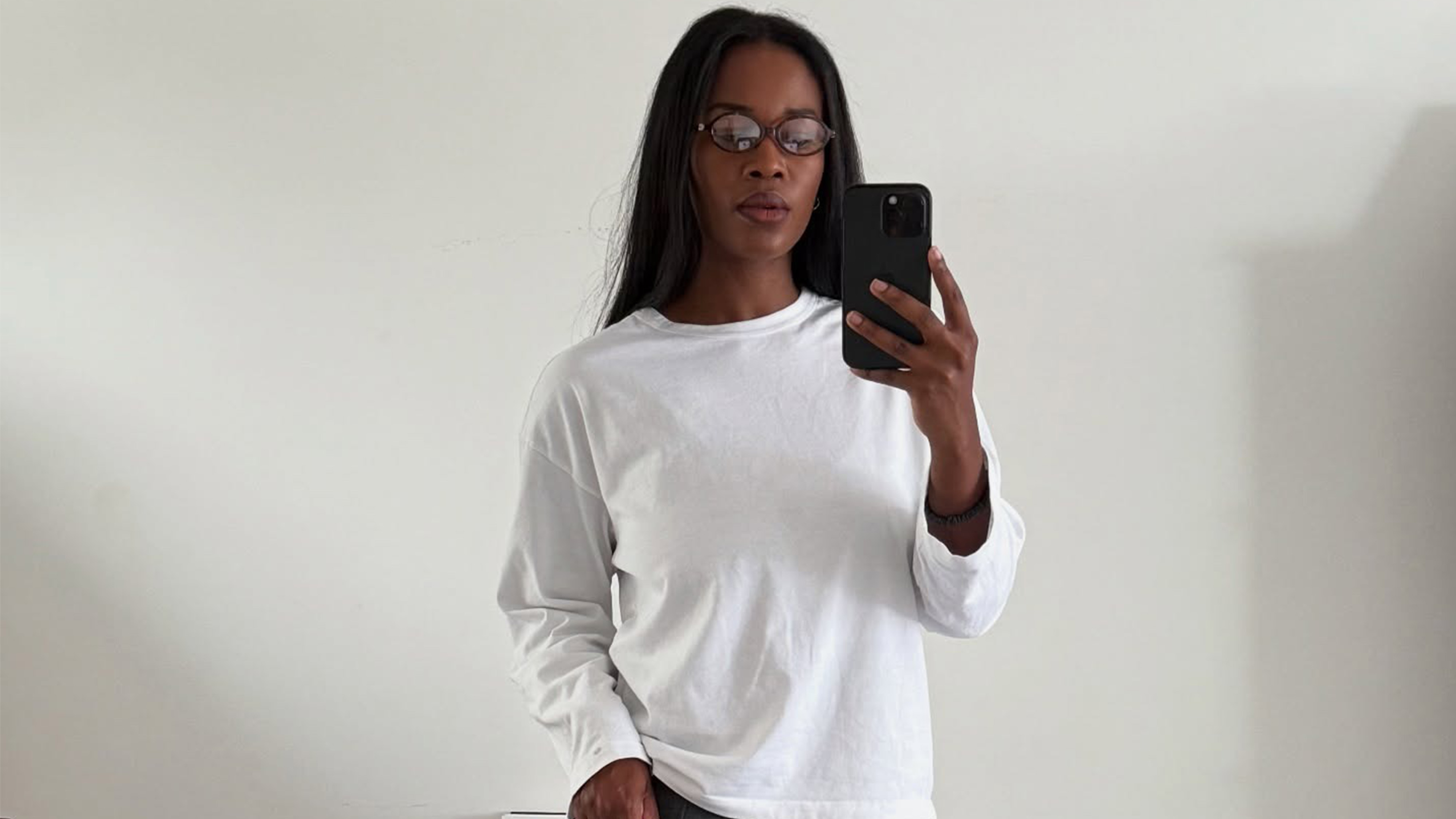 Marilyn wears glasses and a white long-sleeve shirt.