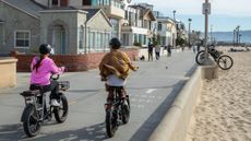 People ride e-bikes on the beach in Hermosa Beach, California.