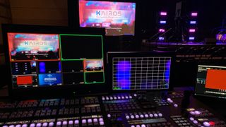 A control panel lit up with purple and blue buttons with Panasonic Connect Kairos software displayed on the montiors.