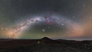 the milky way arched over a dark landscape