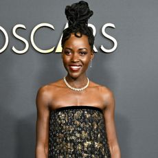 lupita nyongo on the 2024 governors awards red carpet wearing a chanel strapless dress and a tall updo