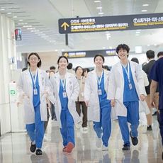 Four doctors walk down a crowded hallway, in 'Resident Playbook.'