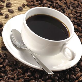 black coffee with coffee beans and white cup with spoon