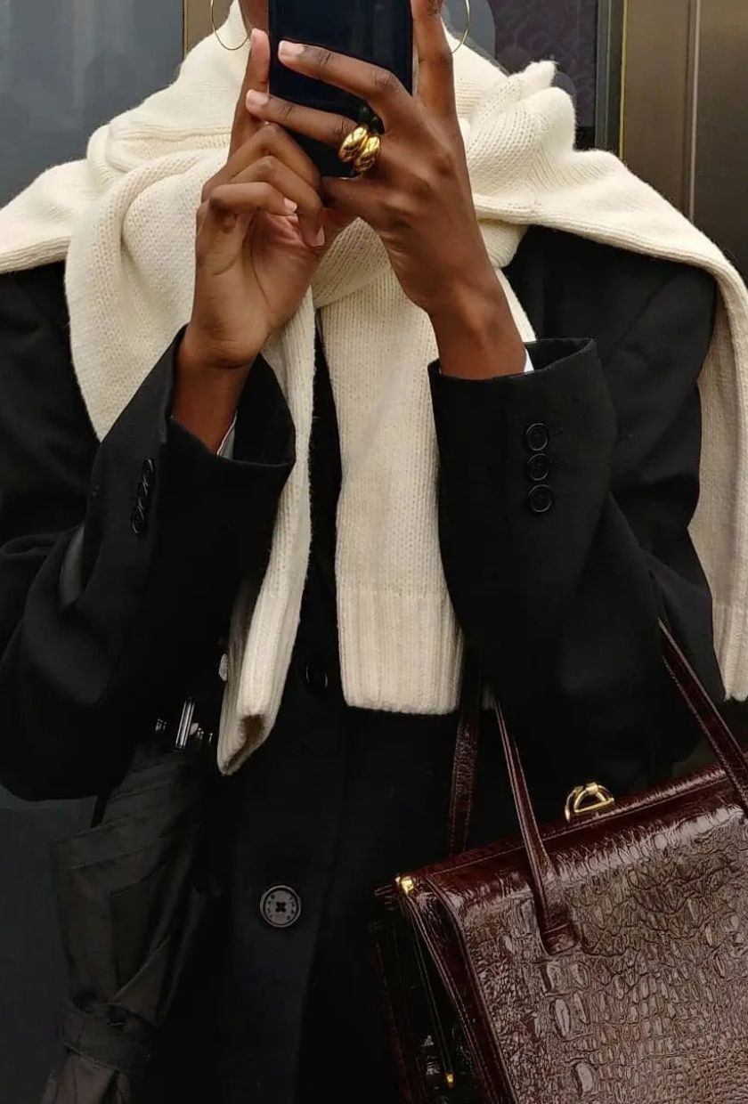 A photo of @sylviemus_ taking a selfie, wearing a cream jumper wrapped over a black blazer and carrying a burgundy bag