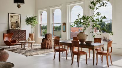 open plan dining and living room with white ealls, large windows and antique furniture
