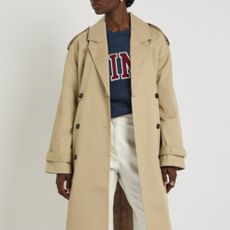 Woman wearing Harvey Nichols trench coat, jumper, and white jeans