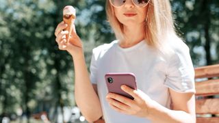 woman with ice cream holding phone on sunny day