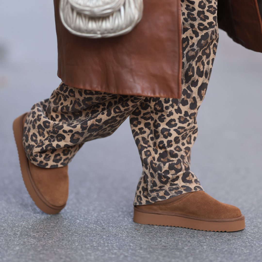 Karin Teigl is seen wearing a calf-length brown leather coat from Prada, wide jeans in leopard print from Bershka, a silver metallic “Wandler“ bag from Miu Miu, and brown suede platform slippers from Copenhagen Studios on November 05, 2024 in Vienna, Austria. (Photo by Jeremy Moeller/Getty Images)