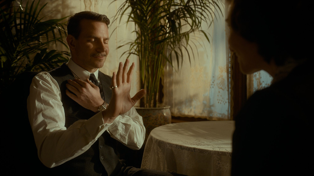 Bradley Cooper performs a psychic reading in Nightmare Alley, a film directed by Guillermo del Toro.