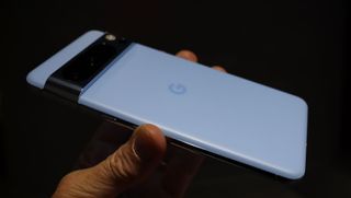 En hånd holder i en lyseblå Google Pixel 8 Pro.