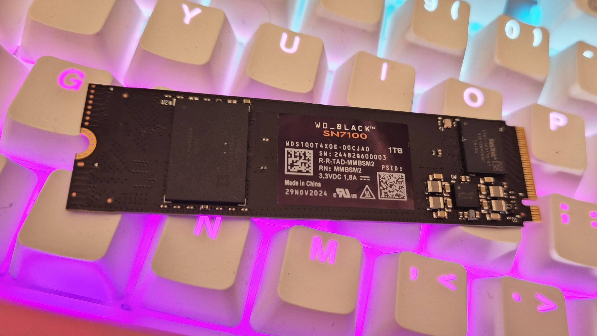 Close up of a black SSD sitting on top of a gaming keyboard.