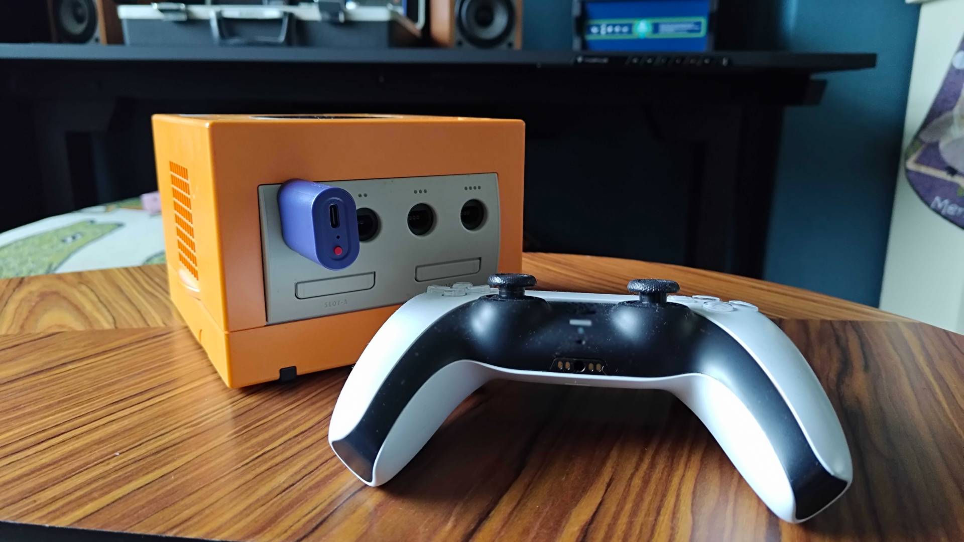 8Bitdo Retro Receiver plugged into orange GameCube next to PS5 DualSense.