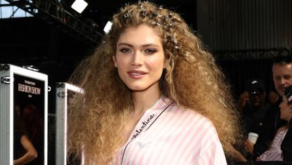 Valentina Sampaio gets ready backstage at the 2024 Victoria&#039;s Secret Fashion Show wearing a striped Victoria&#039;s Secret robe and teased curls