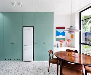 A mint colored kitchen storage that goes up to the ceiling