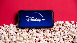 App Disney Plus su uno smartphone, immerso tra i popcorn da una vista BirdSeye