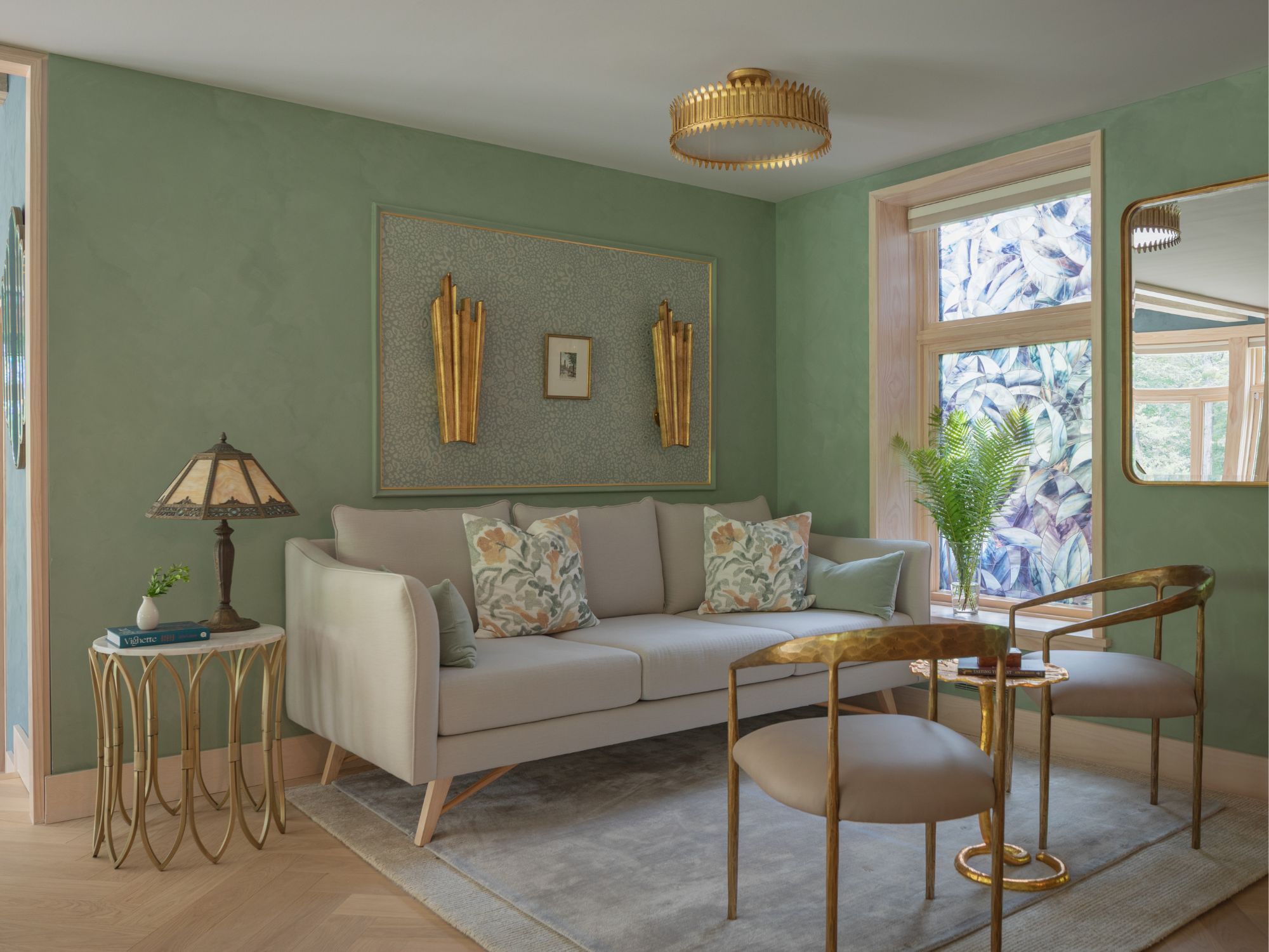 Green living room with gold lamp, chairs, grey sofa and two rugs placed one on top of each other