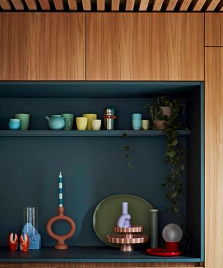 dark green kitchen alcove and worktop with open shelf display storage and colourful ceramics