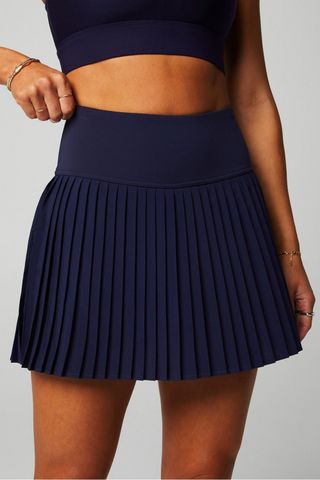 a model wears a navy blue tennis skirt with pleats