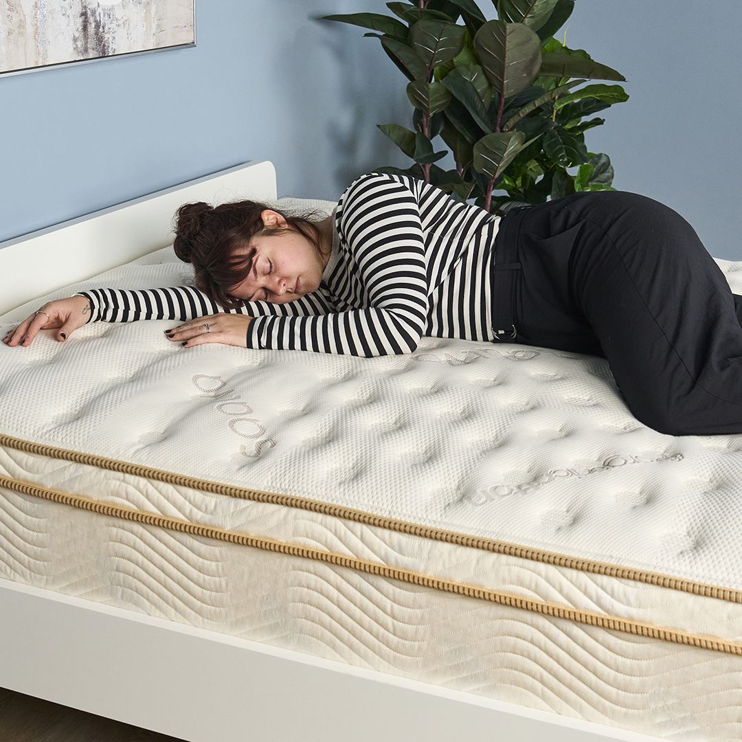 Tom's Guide Sleep Features Editor lies on her side on the Saatva Classic mattress during a testing panel review session at our sleep studio