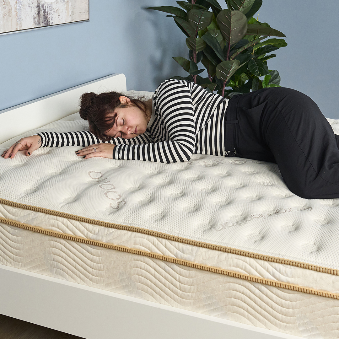 Tom's Guide Sleep Features Editor lies on her side on the Saatva Classic mattress during a testing panel review session at our sleep studio