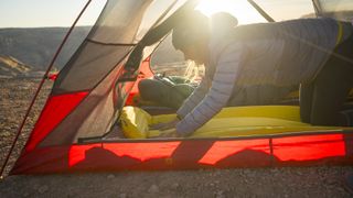 Woman laying down sleeping pad inside tent