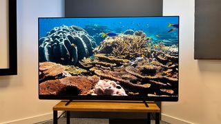 Philips OLED909 OLED TV on wooden hi-fi bench showing underwater scene on screen