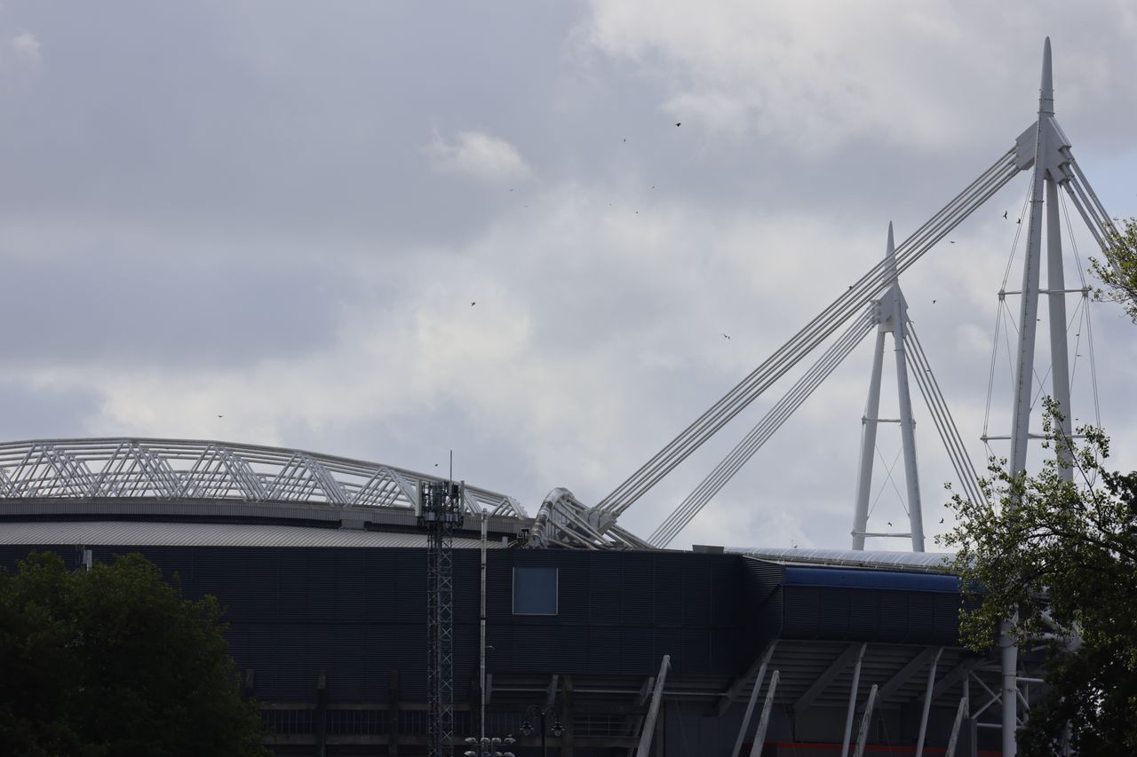 The roof of a stadium in front of a cloudy sky