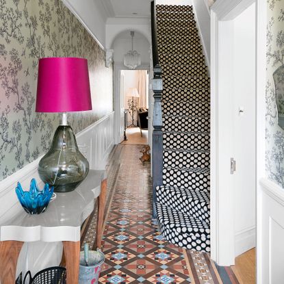 Hallway full of patterned with wallpaper, patterned floor tiles and spotty carpet on the stairs