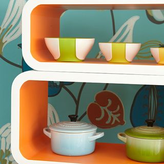 orange shelves with bowls and wallpaper on wall
