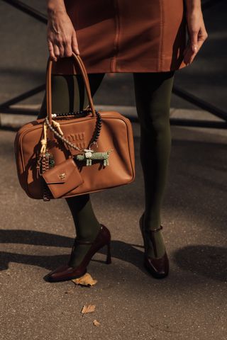 a woman at paris fashion week carries a miu miu bag