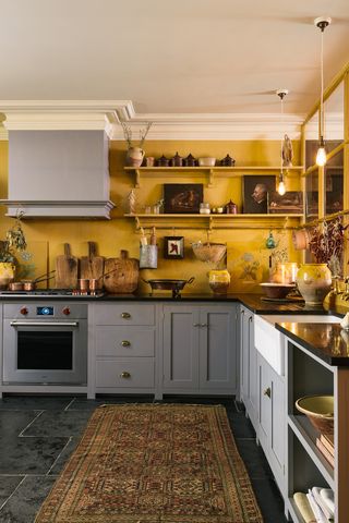 Eclectic yellow kitchen filled with curios with partition windows on one wall and rug on the floor