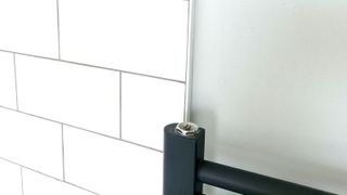 White metro tile with white trim next to grey wall and grey radiator