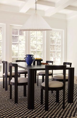 Modern dining room with black wood dining table, matching rounded wooden dining chairs, checked rug, large white pendant over table