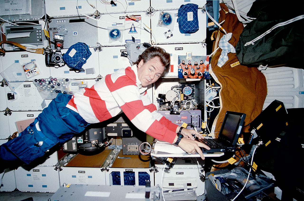 STS-85 Payload Specialist Bjarni Tryggvason, representing the Canadian Space Agency, records data from the Microgravity Vibration Isolation Mount (MIM) experiment on the middle deck of the Space Shuttle Discovery in August 1997.
