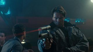 A still from The Terminator, with Arnold Schwarzenegger's T-800 holding someone at gunpoint