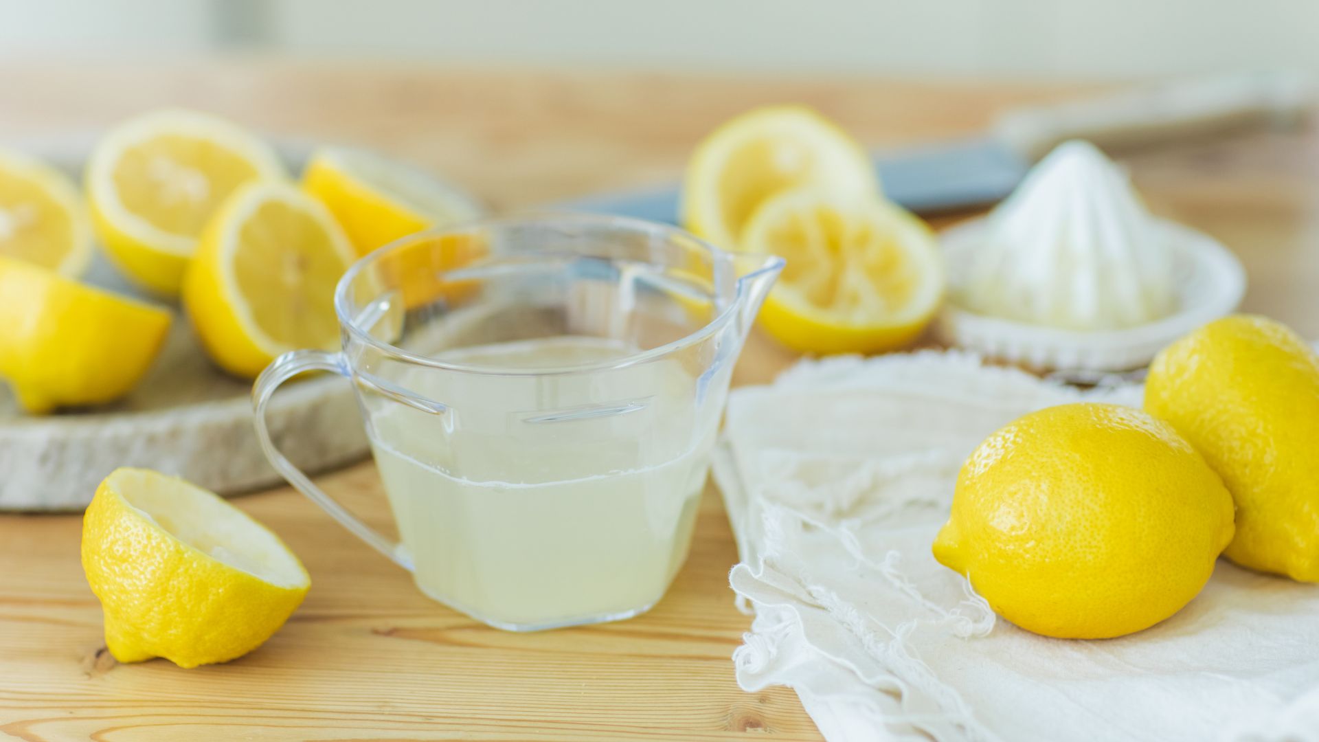 picture of jug filled with squeezed lemon juice and several lemons surrounding it