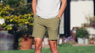 A white man wears a pair of olive shorts and w white tshirt.