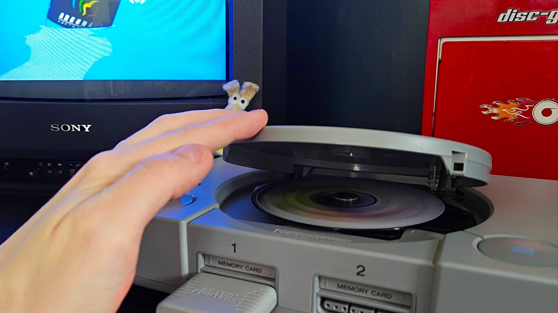 Hand pressing PS1 disc cover down as disc spins inside.