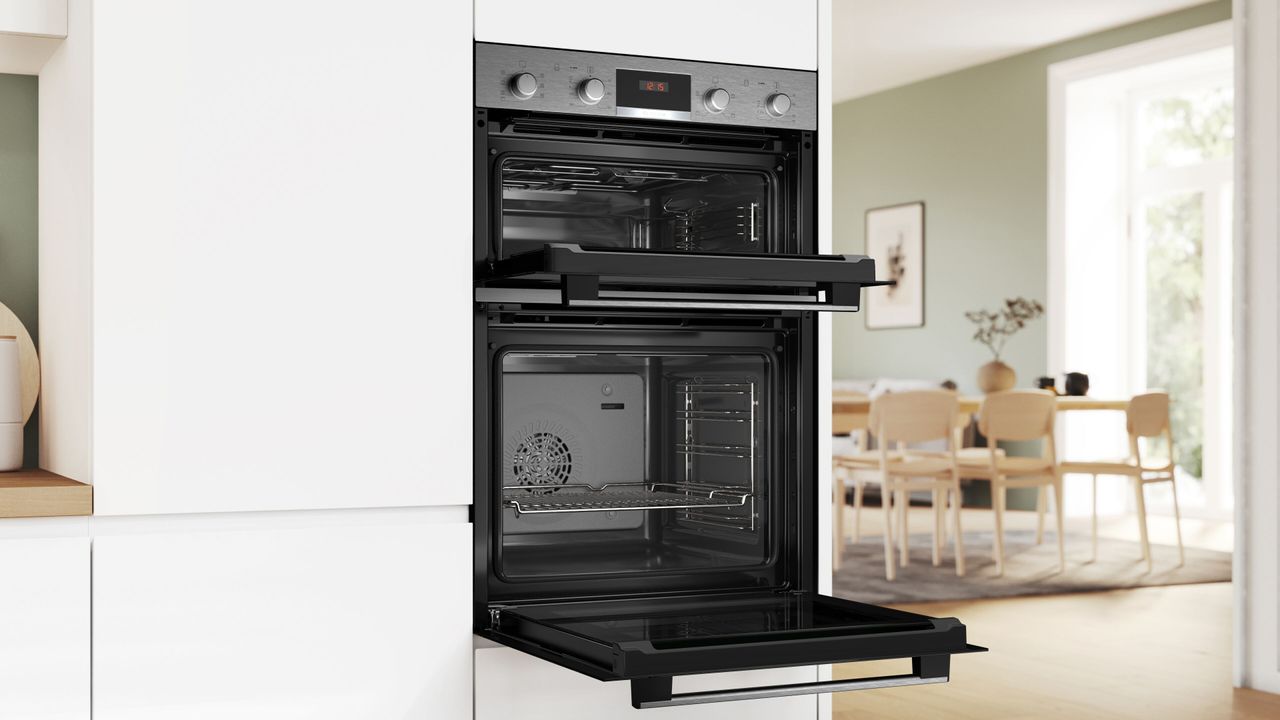 A kitchen with white cabinets, and a double oven