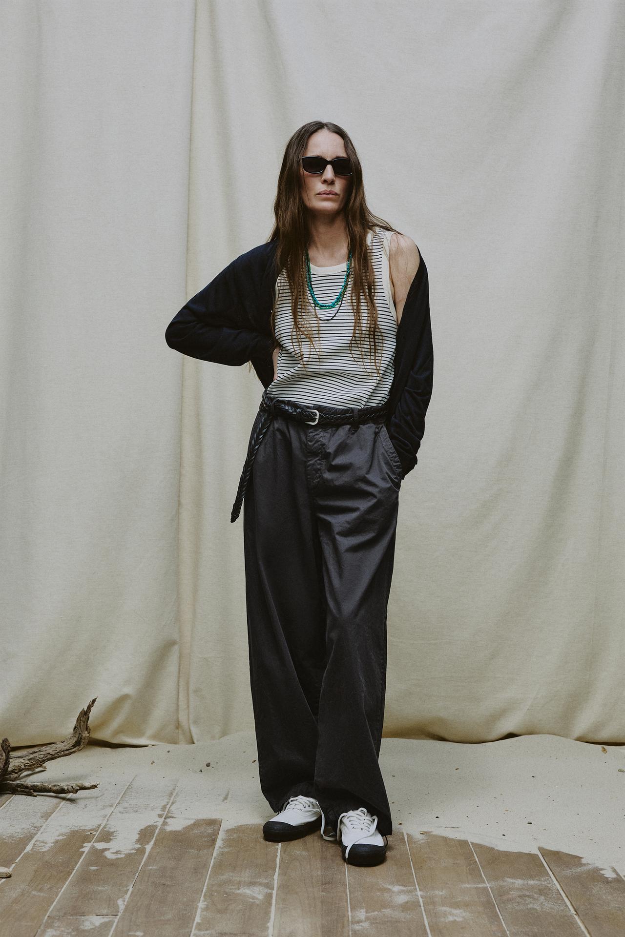 Model wears striped tank, black cardigan, gray pants, and white sneakers.