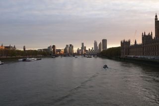 Sun setting over the River Thames with the Houses of Parliament on the right and large tower blocks in the distance