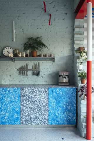 Kitchen with blue and black patterned counter and grey wall shelving.