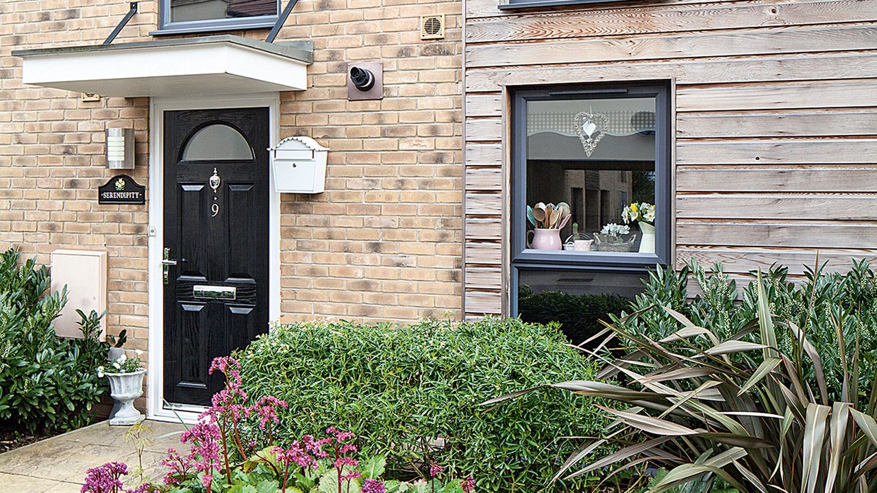 Exterior of a modern brick house with black front door and small canopy