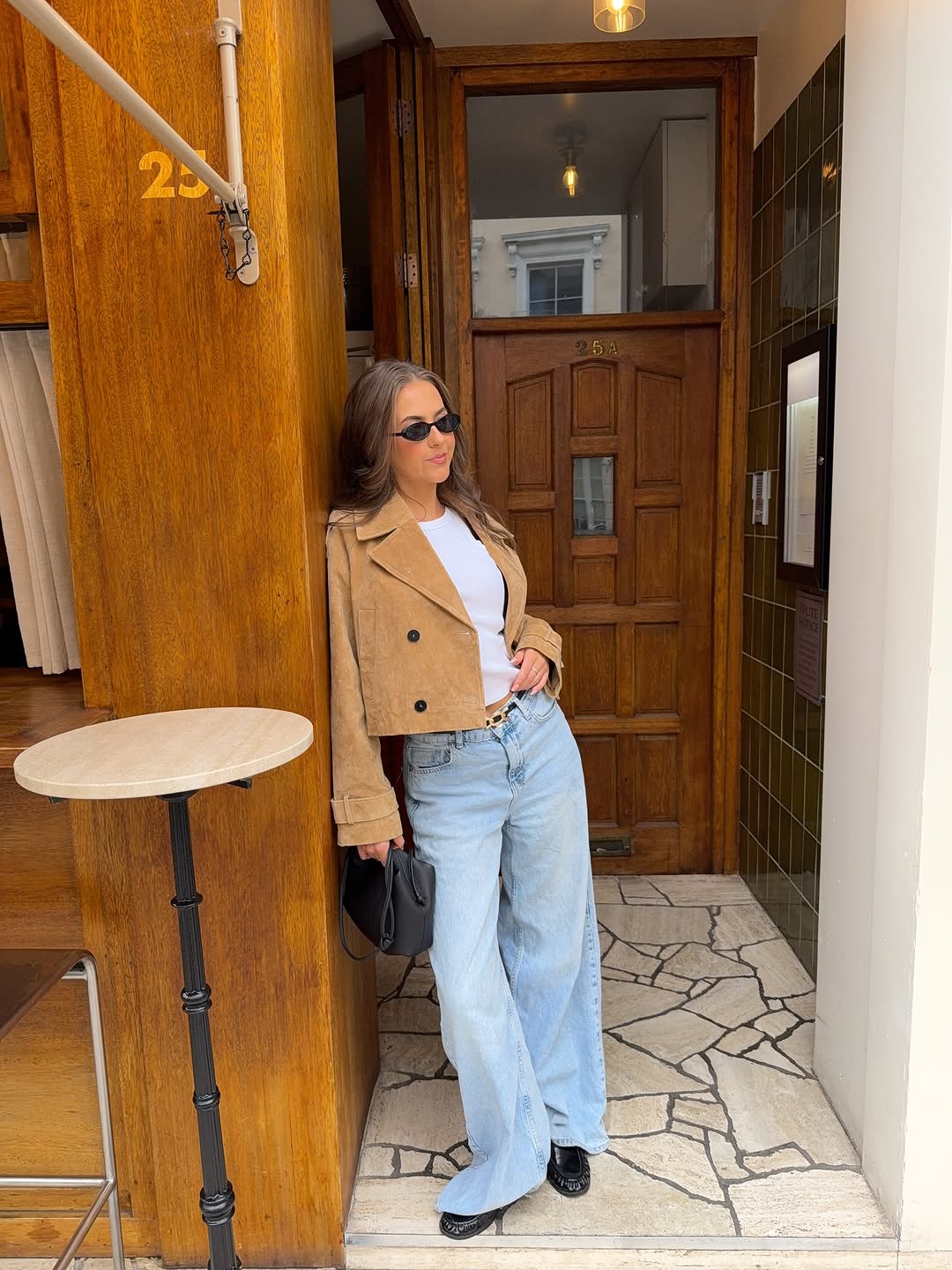 Woman wearing a tan jacket with jeans in a fall 2025 outfit.