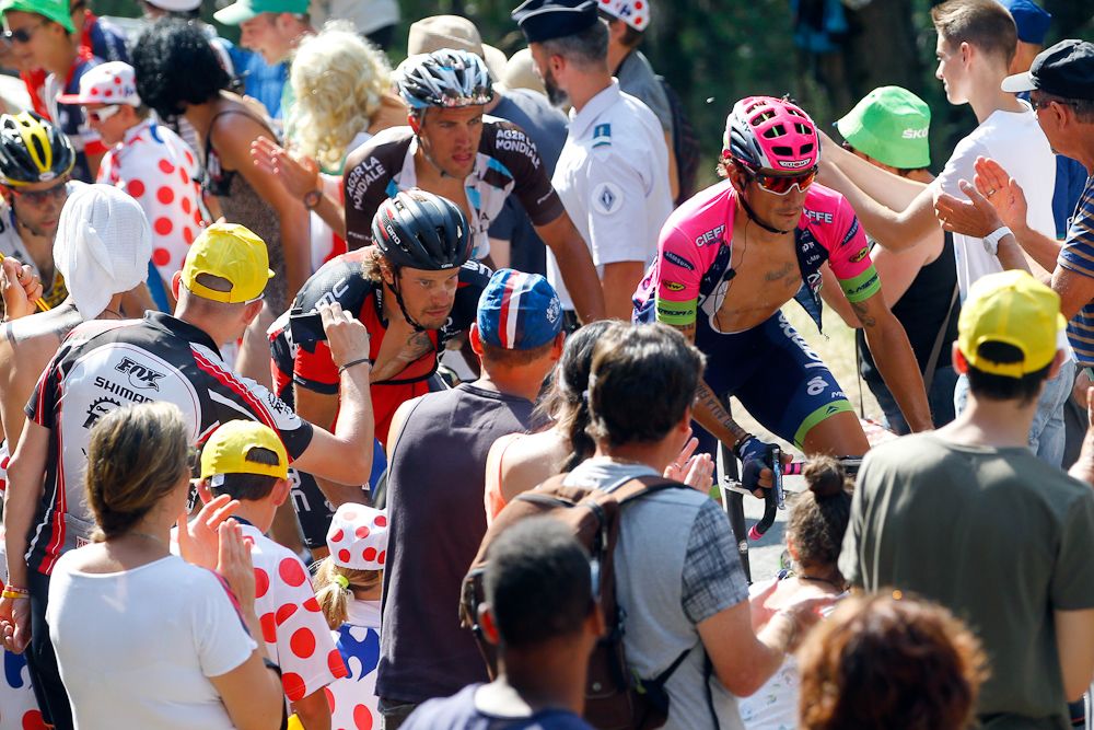 Riders make their way through the throng of spectators during stage 14.