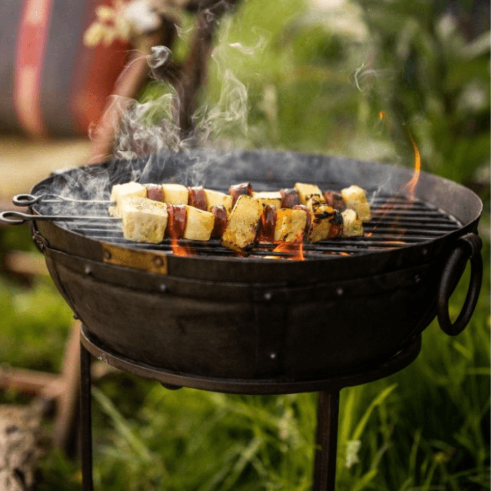 A Kadai travel BBQ grilling sticks of pineapple and meat