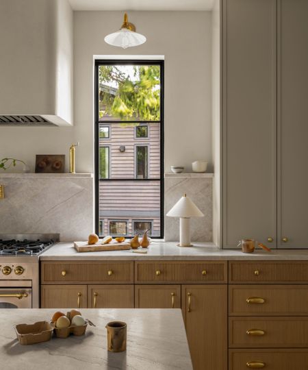 A classic kitchen with white upper cabinets, wood lower cabinets with fluted drawers, and marble countertops
